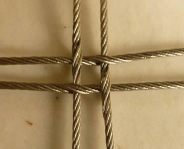 A piece of cross-shaped stainless steel square rope mesh is on the floor.