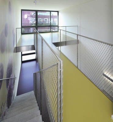 Stainless steel ferrule rope mesh is installed as the balustrade infill of concrete stair and yellow passage.